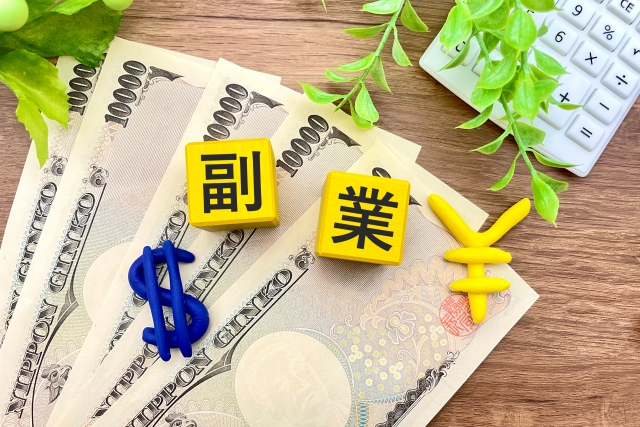 一万円札の上に副業という文字が書いてあるキューブの写真