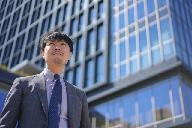 会社の前に立っているビジネスマンの写真