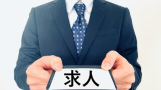 求人と書かれた紙を差し出す就職活動中の男性の写真